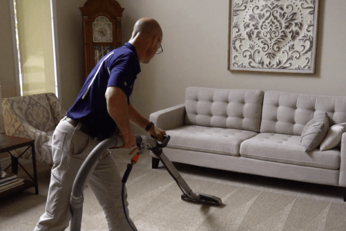 Professional cleaning carpet in front of beige couch